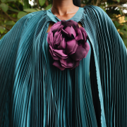 Fabric Elegant teal pleated cape gown with bold floral appliqué