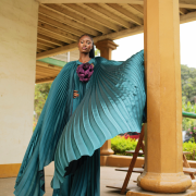 Fabric Elegant teal pleated cape gown with bold floral appliqué