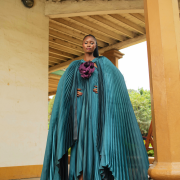Fabric Elegant teal pleated cape gown with bold floral appliqué